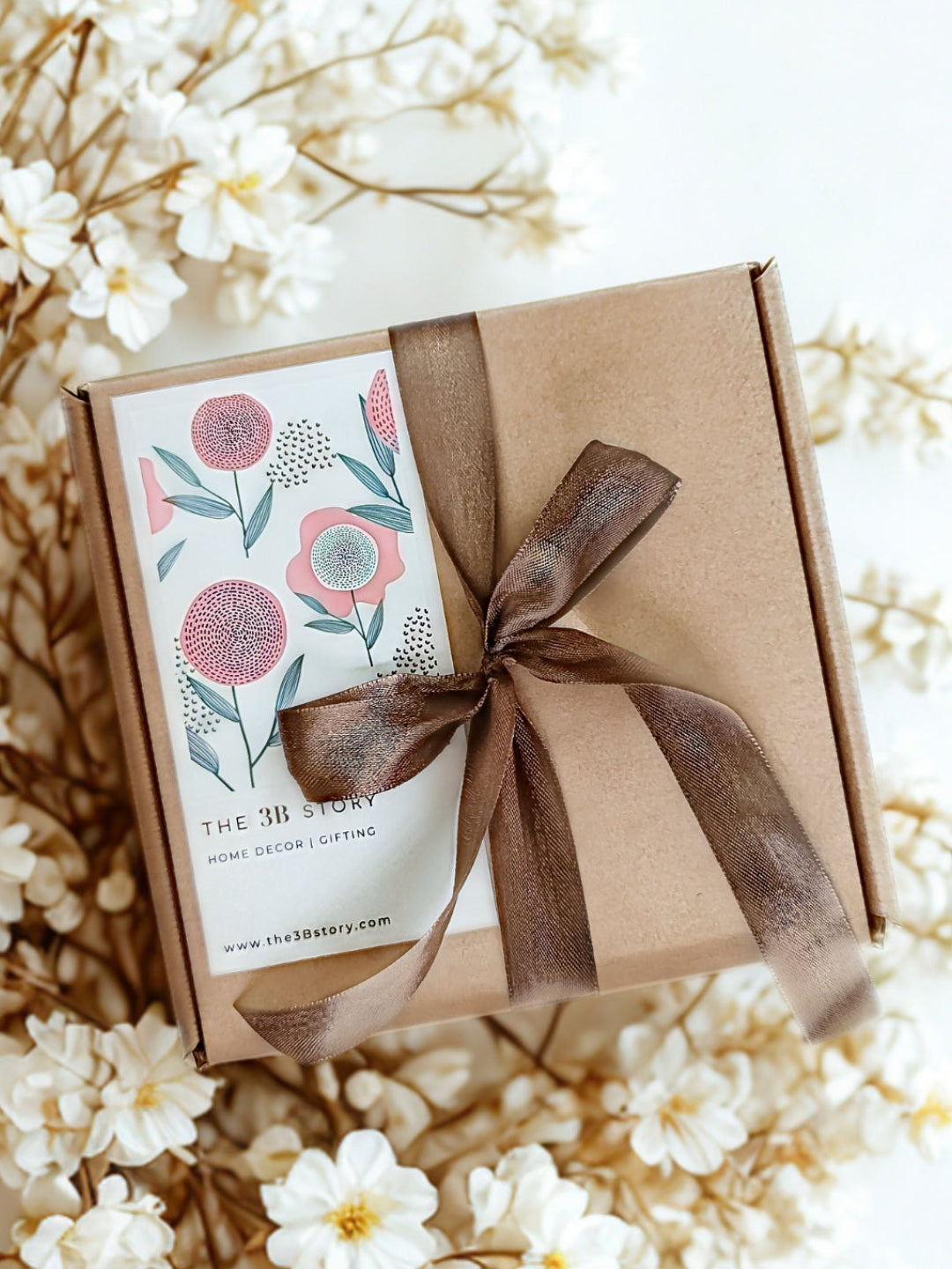 Gift box with floral design label and brown ribbon on a floral background